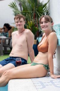 un homme et une femme assis à côté d'une piscine dans l'établissement The View Hostel & Lounge, à Cali