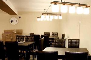 una sala da pranzo con tavoli, sedie e orologio di Hotel Abu a Gudauri
