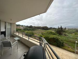 a balcony with chairs and a view of a field at Full equipado frente al mar 4307 in Los Molles