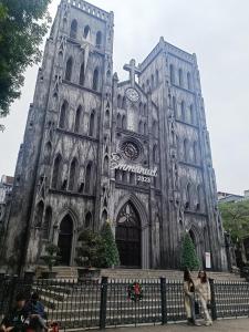 an old cathedral with people standing in front of it at Hoan Kiem lake center in Hanoi