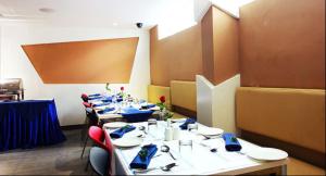 una sala da pranzo con tavoli lunghi e sedie rosse di Millennium Continental a Cochin