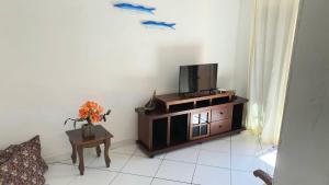 a living room with a tv on a cabinet with a table at Suite Baia dos Corais Praia de Provetá Ilha Grande in Angra dos Reis