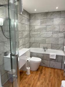 a bathroom with a tub and a toilet and a sink at The Randolph Hotel in Southwold