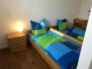 2 Betten mit blauen und grünen Kissen in einem Zimmer in der Unterkunft Aparthotel Ochsenfurt mit Terrasse für aktive Reisende in Ochsenfurt