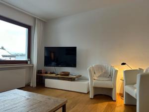 - un salon avec une télévision et deux chaises dans l'établissement Haus Leni am Paulsberg, à Braunlage