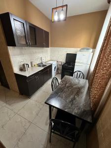eine kleine Küche mit einem Tisch, einem Waschbecken und einer Theke in der Unterkunft Hotel M.Classic in Tbilisi City