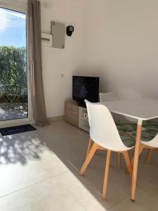 een woonkamer met een tafel en stoelen en een televisie bij Maisonnette dans belle résidence in Saint-Vallier-de-Thiey