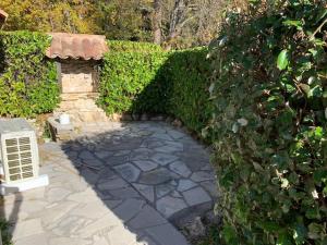 einen Garten mit einem Steingang neben einer Hecke in der Unterkunft Maisonnette dans belle résidence in Saint-Vallier-de-Thiey