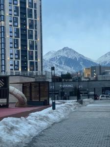 una calle nevada con edificios y montañas en el fondo en Квартира посуточно Алматы en Almaty