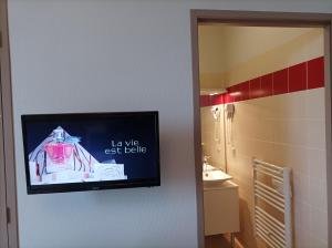 TV en la pared del baño en Auberge de Mourjou, en Mourjou