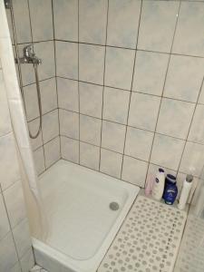 y baño con ducha y pared de azulejos blancos. en Stan na dan Apartman Kozarac, en Kozarac