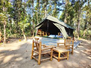 einen Pavillon mit zwei Stühlen und einem Tisch davor in der Unterkunft Athulyam Kanha, kanha national park, mukki gate in Khāpa