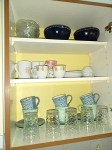 a shelf filled with bowls and cups and plates at Stan na dan Apartman Kozarac in Kozarac +6 photos