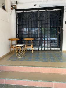 two tables and two stools in front of a door at Homestay Dyzas in Batu Caves