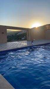 a swimming pool with the sunset in the background at Gernath farm in Ajloun