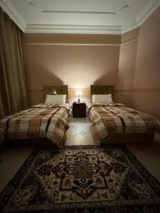 two beds in a room with a rug at Luxurious Hilltop Apartment 9 minutes from Haram in Makkah