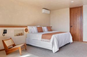 1 dormitorio con cama grande y silla de madera en Dreamland Bungalows - Taipú de Fora - Barra Grande, en Barra Grande