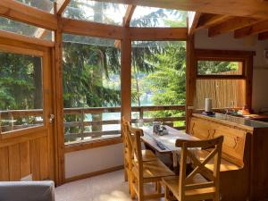 cocina con mesa, sillas y ventanas en BOG Le Pommier - Cabañas con vista al lago y piscina climatizada en Villa La Angostura