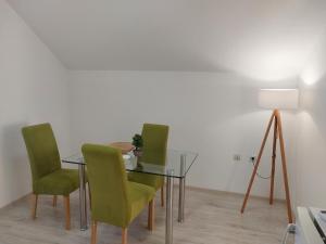 a dining room with a glass table and green chairs at Studio Andrijana Sokobanja in Soko Banja