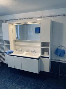 W łazience znajduje się biała umywalka i lustro. w obiekcie Apartments Arcadia w mieście Saas-Grund