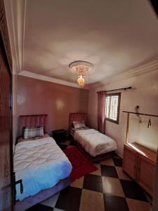 a bedroom with two beds and a checkered floor at taghazout life Guest House in Taghazout