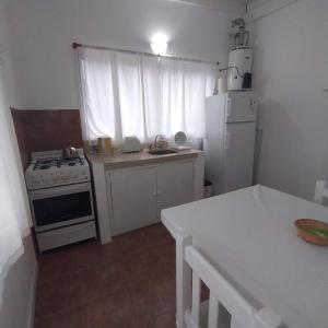 eine Küche mit einem weißen Herd und einem weißen Kühlschrank in der Unterkunft Acacia in Pinamar
