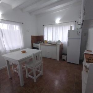 eine Küche mit einem weißen Tisch und einem weißen Kühlschrank in der Unterkunft Acacia in Pinamar