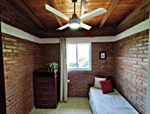 a ceiling fan in a room with a brick wall at Departamento Olmos in Mina Clavero
