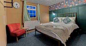 - une chambre avec un lit et une chaise rouge dans l'établissement Bay Tree Cottage, sleeps 7 close to the Marina, à Burnham on Crouch