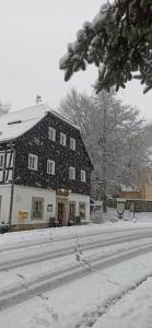 ein Haus ist mit Schnee bedeckt in einem Hof in der Unterkunft Gasthof Alte Schmiede G*** Lückendorf in Luftkurort Lückendorf