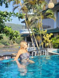 a woman sitting in the water in a swimming pool at Peacock Village Pinnawala in Pinnawala