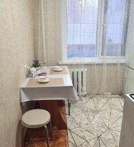 a kitchen with a table and a stool and a window at 1 к квартира в Центре Мухита д 128 in Uralsk