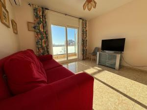 a living room with a red couch and a television at Piso en el centro con vistas al mar y balcón in Roses