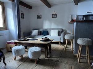 een woonkamer met een bank, een tafel en 2 krukken bij La Combe de Moulin in Peisey-Nancroix