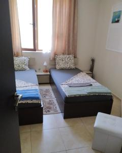 Habitación pequeña con 2 camas y ventana en Апартамент Анастасия Аполон 6, en Ravda