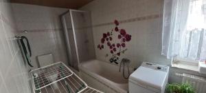 a bathroom with a tub and a washing machine at Ferienwohnung Schwarz in Lauter