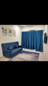 Homestay Fayyadh Teluk Intan 3Room2Bath في تيلوك إنتان: غرفة معيشة مع أريكة زرقاء ونافذة
