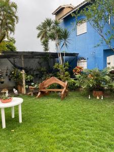 a garden with a table and a blue house at Cantinho dos Machados in Camaçari