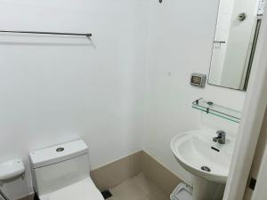 a white bathroom with a toilet and a sink at Ever Stays at Light Residences 1BR in Manila