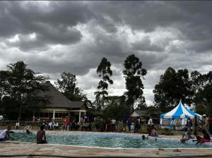 une piscine avec une tente et des personnes debout autour de celle-ci dans l'établissement Lulunga Eco Lounge and Farm, à Narok