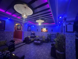 a room with purple lighting and couches and chairs at Maison d'hôtes Afassi in Chefchaouen