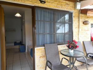 a patio with a table and chairs and a window at Bambola Apartments in Nea Moudania