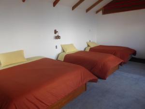 three beds in a room with red comforters at CAMPO SANTO in Comunidad Yumani