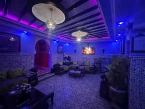 a room with purple lighting and couches and tables at Maison d'hôtes Afassi in Chefchaouen