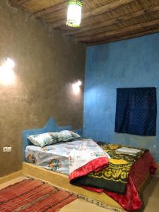 uma cama num quarto com uma parede azul em DAR AMMAR em Merzouga