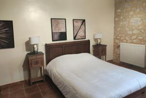 een slaapkamer met een wit bed en 2 nachtkastjes bij Chambre d'hôte la source in Conne-de-Labarde