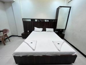 1 cama con sábanas blancas y espejo en una habitación en Parth Hotel, en Navi Mumbai