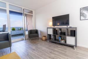 a living room with a flat screen tv and a large window at Koje Seaside in Harrislee