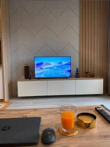 uma mesa com um copo de sumo de laranja e uma televisão em Apartman Breza - Vila Umine Vode em Zlatibor