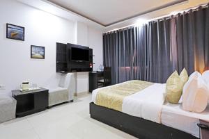pokój hotelowy z łóżkiem i telewizorem z płaskim ekranem w obiekcie Airport Hotel Swan Near Delhi Airport w Nowym Delhi